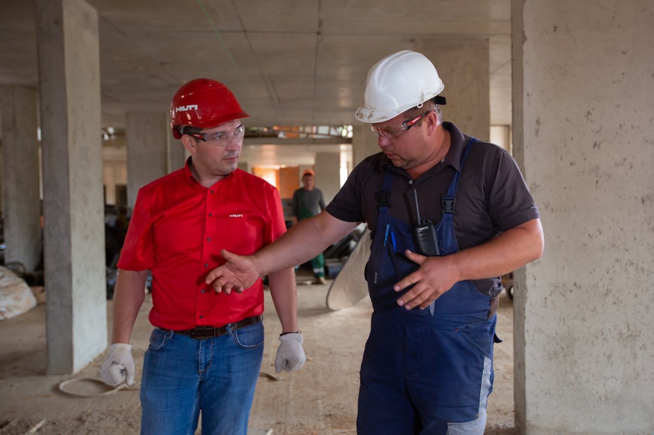 Mastering the First Impression: Your intriguing post title goes here Two construction workers in safety gear discussing plans at a construction site.